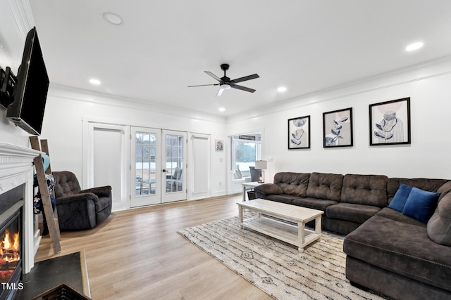 living room featuring light hardwood / wood-style flooring, ceiling fan, and ornamental molding