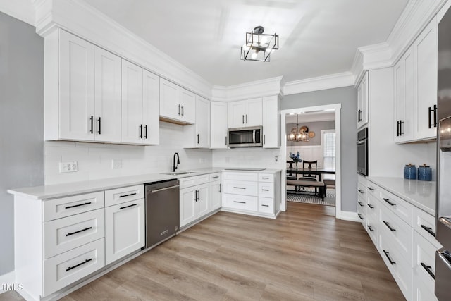 kitchen featuring light wood-type flooring, stainless steel appliances, white cabinetry, and ornamental molding