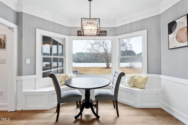 dining space with light wood-type flooring, an inviting chandelier, and crown molding