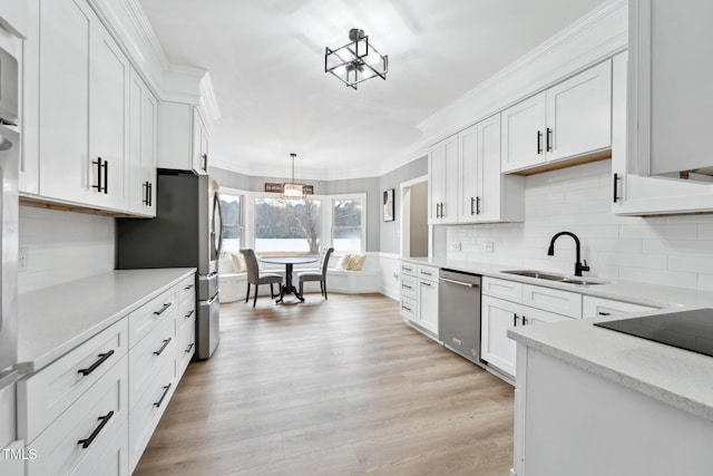 kitchen featuring white cabinetry, sink, stainless steel appliances, light hardwood / wood-style floors, and decorative light fixtures