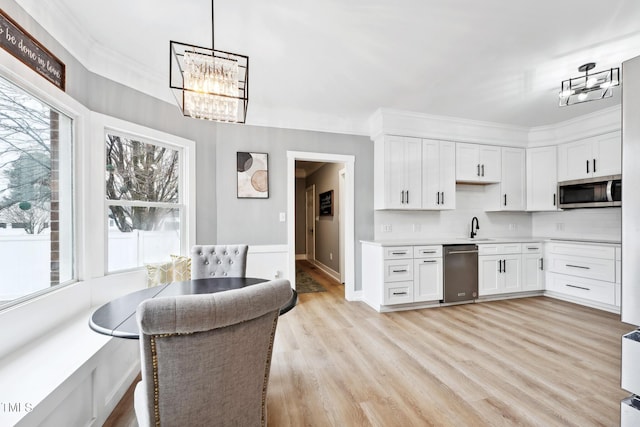 kitchen with sink, white cabinetry, stainless steel appliances, and hanging light fixtures