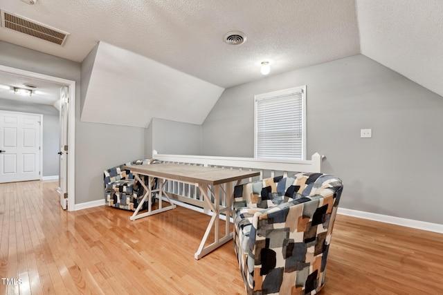 interior space featuring a textured ceiling, wood-type flooring, and vaulted ceiling