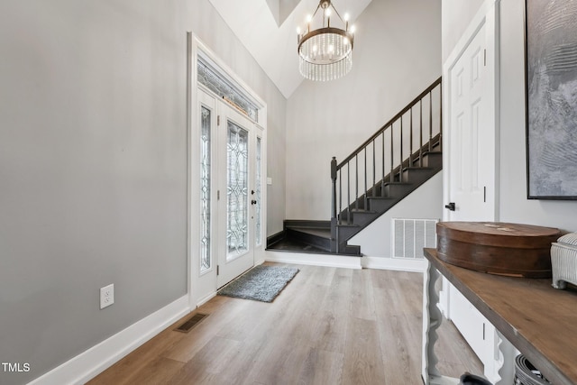 entryway with a chandelier, hardwood / wood-style flooring, and vaulted ceiling