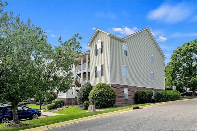 view of side of property with a lawn and a balcony