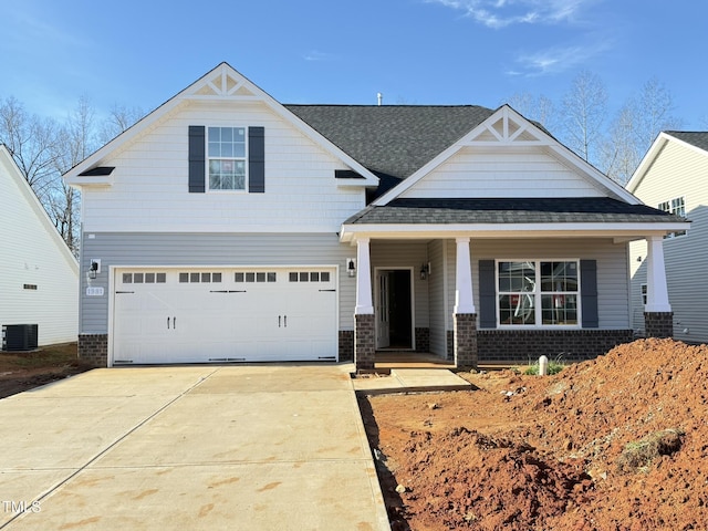 craftsman-style home featuring covered porch, a garage, and central air condition unit