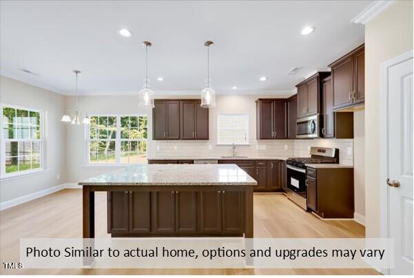 kitchen with hanging light fixtures, a kitchen island, stainless steel appliances, and sink