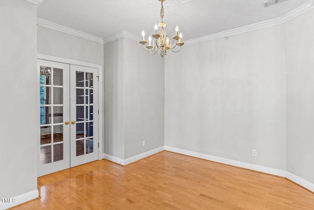 unfurnished room with hardwood / wood-style floors, an inviting chandelier, crown molding, and french doors