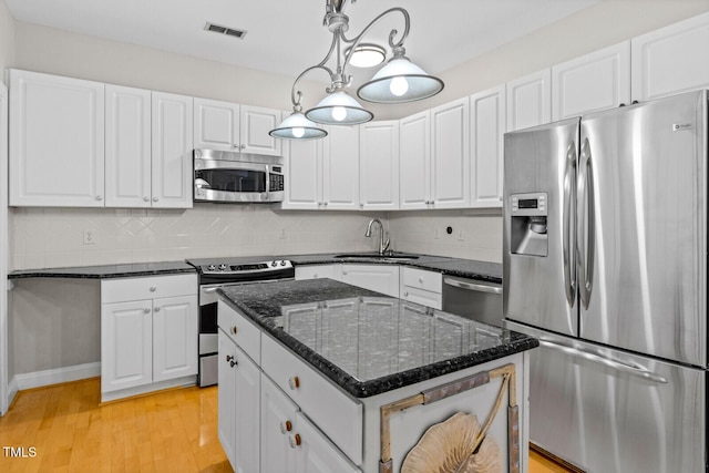 kitchen with white cabinetry, sink, a center island, hanging light fixtures, and appliances with stainless steel finishes