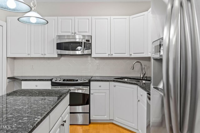 kitchen with pendant lighting, white cabinets, sink, dark stone countertops, and appliances with stainless steel finishes