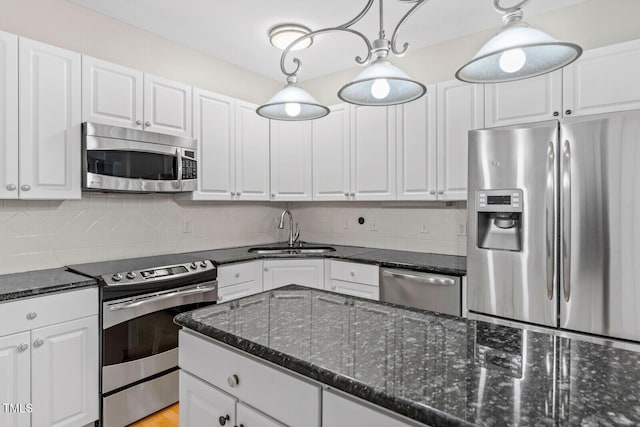 kitchen featuring sink, white cabinets, stainless steel appliances, and decorative light fixtures