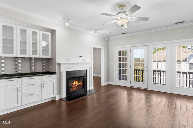 unfurnished living room with dark hardwood / wood-style floors, ceiling fan, and crown molding