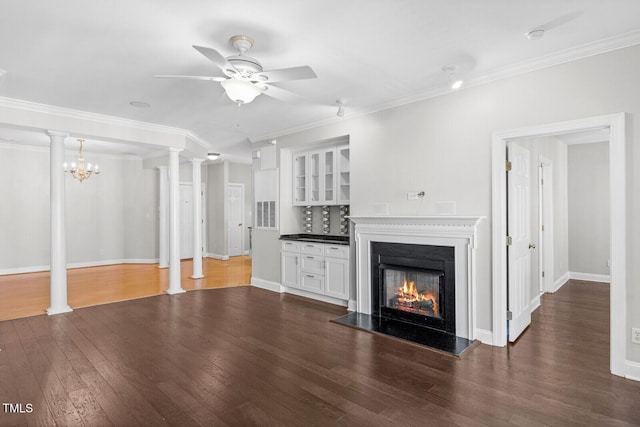 unfurnished living room featuring dark hardwood / wood-style flooring, ceiling fan with notable chandelier, and ornamental molding