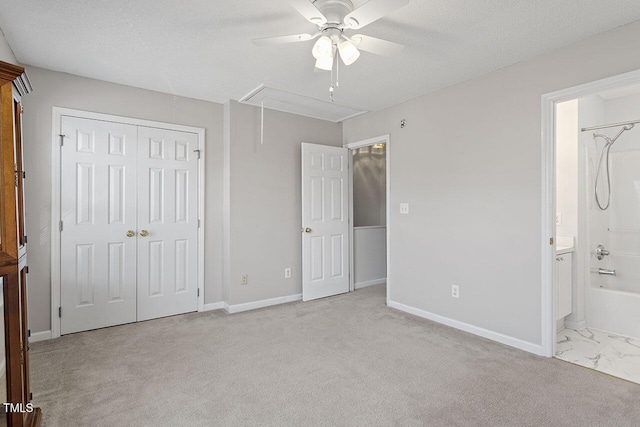 unfurnished bedroom with a textured ceiling, ceiling fan, light carpet, and connected bathroom