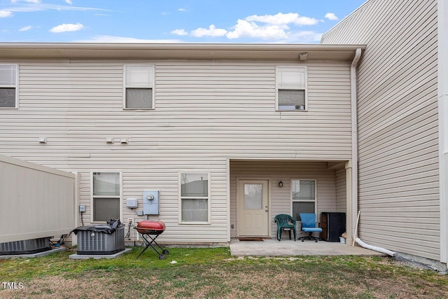 rear view of house with central air condition unit, a patio area, and a yard