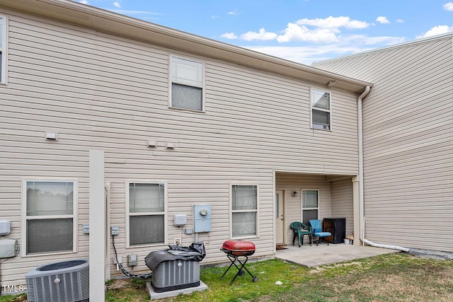 back of house with cooling unit, a yard, and a patio