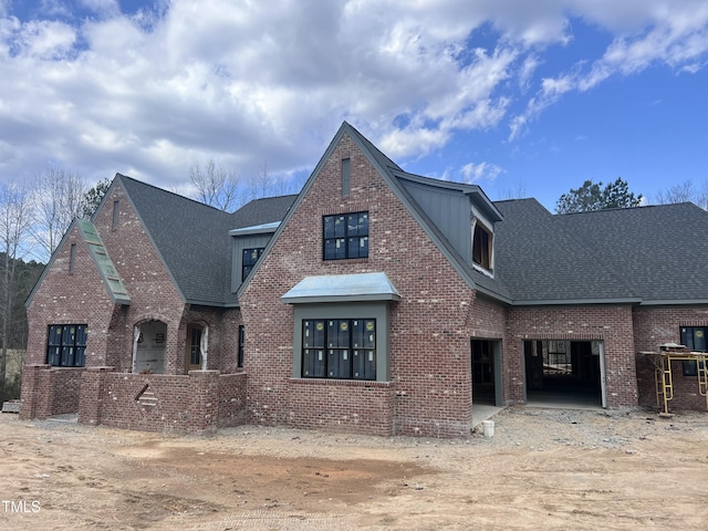 view of front of house with an attached garage, a shingled roof, and brick siding