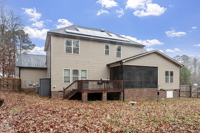 rear view of house featuring solar panels, a deck, and a sunroom