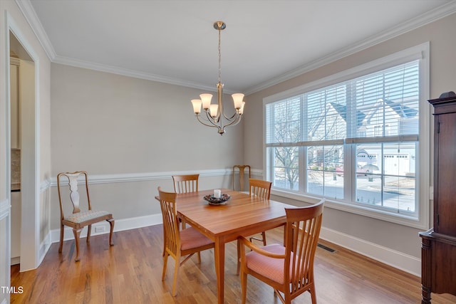 dining space featuring a notable chandelier, ornamental molding, and light hardwood / wood-style flooring