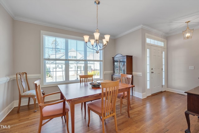 dining space featuring hardwood / wood-style flooring, crown molding, and a chandelier