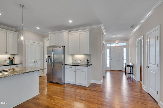 kitchen featuring tasteful backsplash, stainless steel fridge, dark stone countertops, and white cabinetry