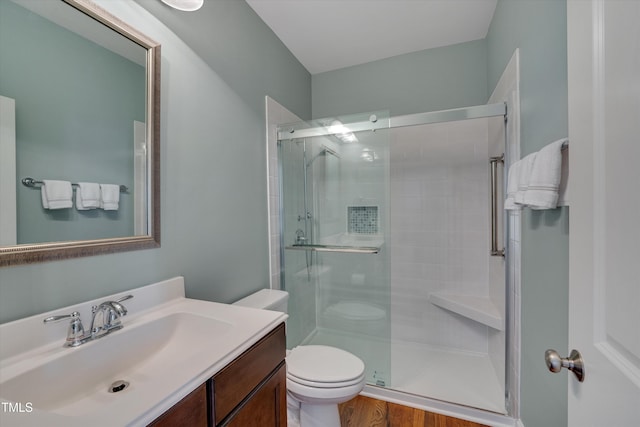 bathroom with vanity, hardwood / wood-style floors, a shower with shower door, and toilet