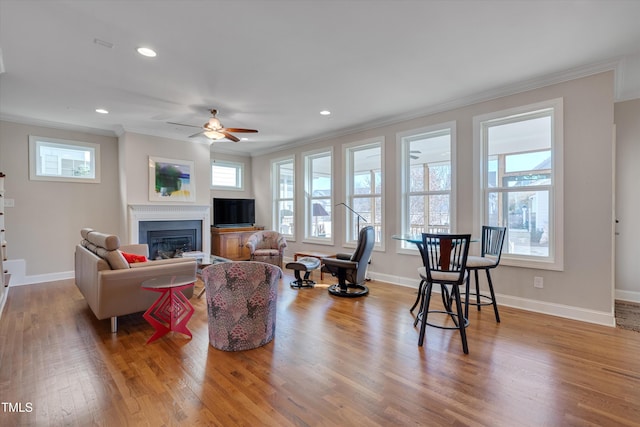 living room with ceiling fan, crown molding, and wood-type flooring