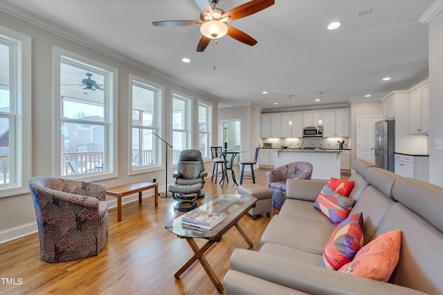 living room with light hardwood / wood-style floors, ceiling fan, and ornamental molding