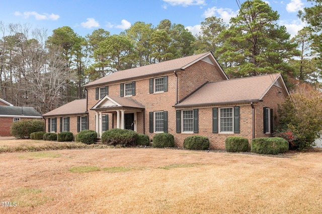 colonial-style house featuring a front lawn