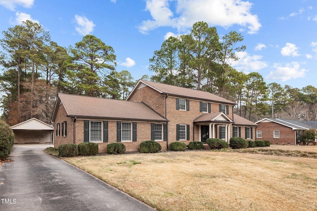 colonial home featuring a carport and a front lawn