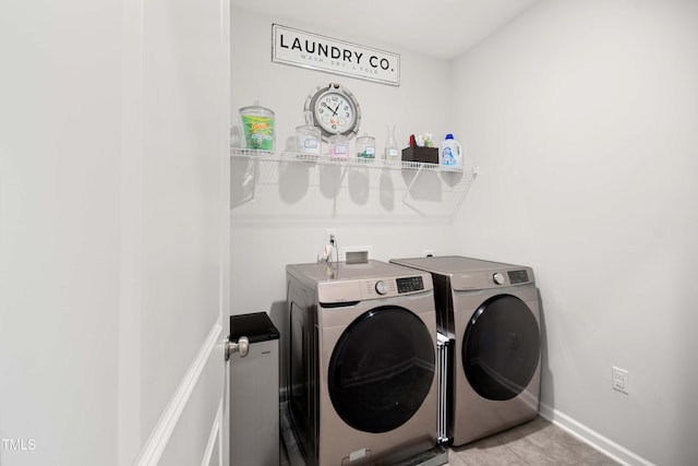 laundry area with light tile patterned floors, baseboards, laundry area, and washer and clothes dryer