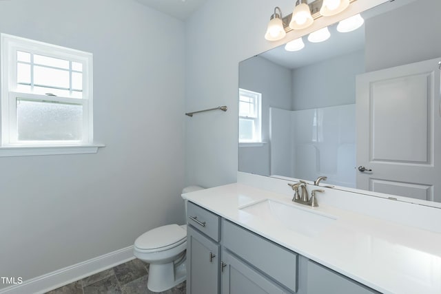 bathroom with vanity, toilet, baseboards, and walk in shower