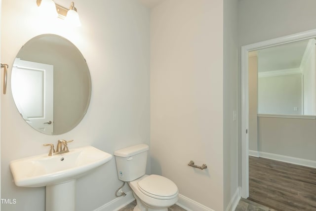 bathroom featuring toilet, wood finished floors, baseboards, and a sink