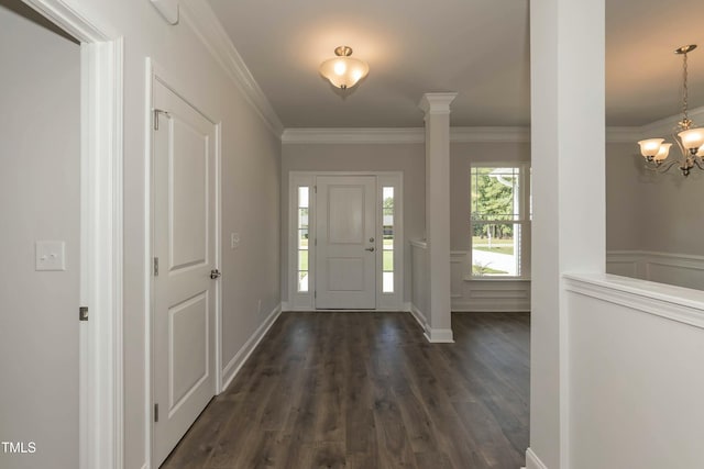 foyer entrance with dark wood-style floors, ornamental molding, wainscoting, a decorative wall, and a notable chandelier