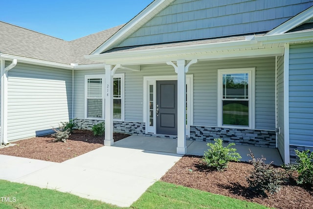 entrance to property with a porch and roof with shingles