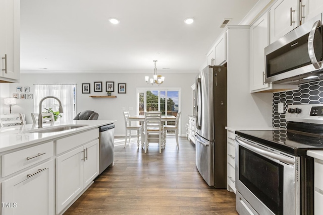 kitchen featuring stainless steel appliances, white cabinetry, ornamental molding, and sink