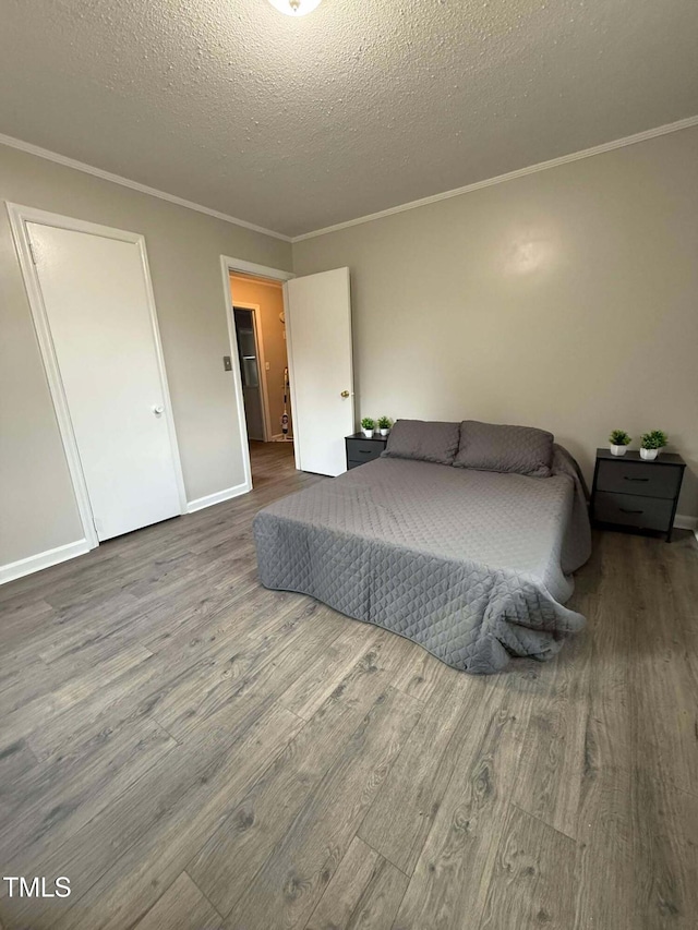 bedroom with a textured ceiling, ornamental molding, and hardwood / wood-style floors