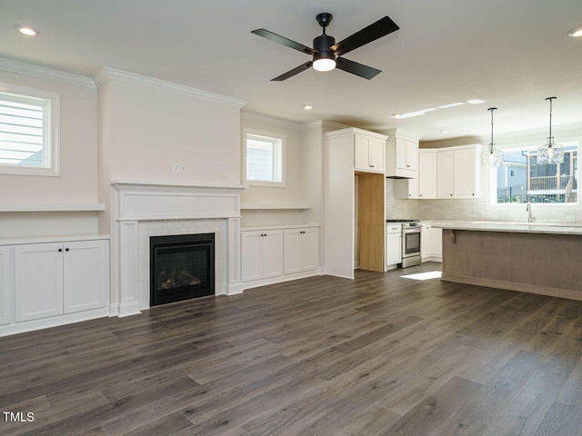 1809 Bright Lantern Way, Wendell, NC 27591 - unfurnished living room with crown molding, plenty of natural light, ceiling fan, a tiled fireplace, and dark wood finished floors