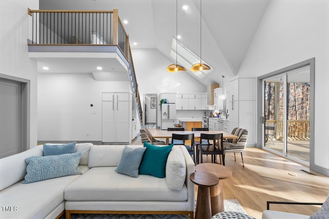 living room with sink, light hardwood / wood-style flooring, and high vaulted ceiling