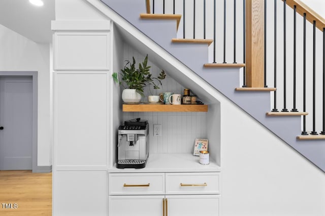 bar with white cabinetry and light hardwood / wood-style floors