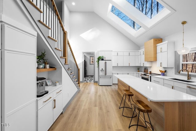 kitchen featuring decorative light fixtures, a center island, electric range, white cabinets, and white fridge with ice dispenser