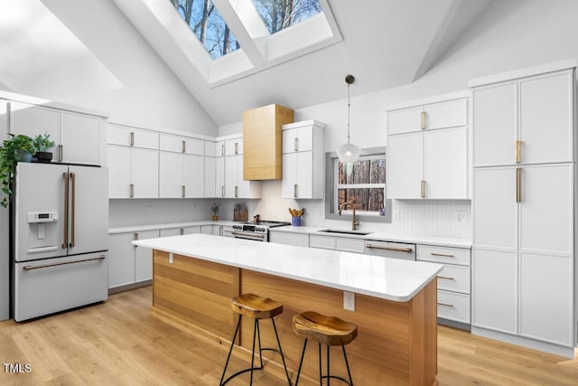 kitchen with tasteful backsplash, sink, a skylight, stainless steel appliances, and high vaulted ceiling