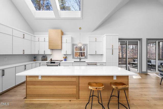 kitchen featuring a skylight, white cabinetry, a kitchen island, and sink