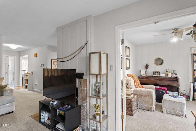 carpeted living room with a textured ceiling and ceiling fan