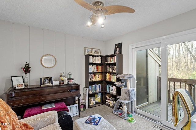 sitting room featuring a textured ceiling, light colored carpet, ceiling fan, and a healthy amount of sunlight