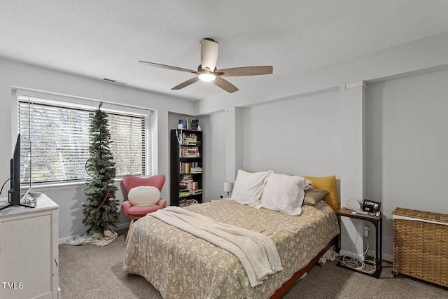 carpeted bedroom featuring ceiling fan and a textured ceiling