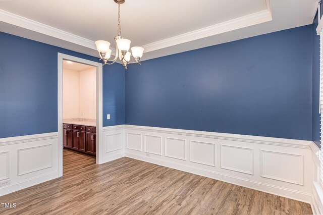 spare room featuring ornamental molding, light hardwood / wood-style flooring, and a notable chandelier