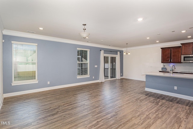 kitchen with crown molding, sink, decorative light fixtures, an inviting chandelier, and dark hardwood / wood-style floors