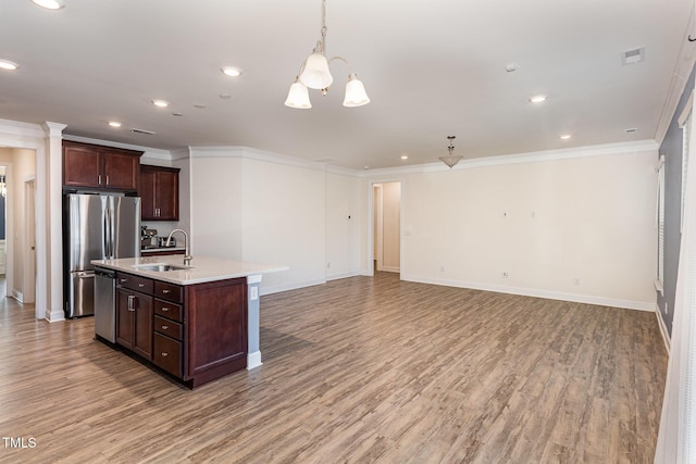 kitchen featuring sink, pendant lighting, a kitchen island with sink, dark brown cabinets, and appliances with stainless steel finishes