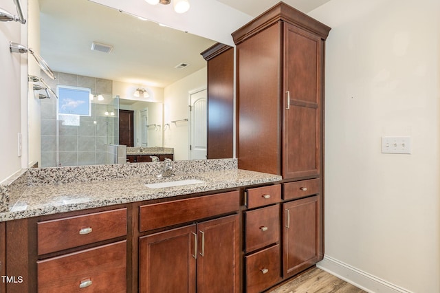 bathroom featuring vanity, a tile shower, and wood-type flooring