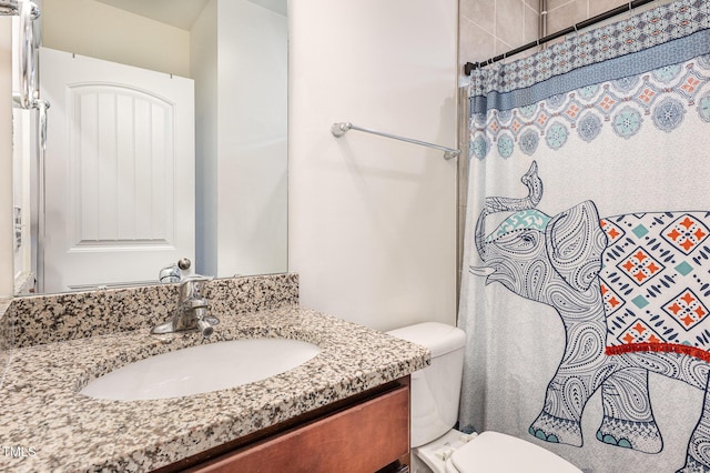 bathroom with curtained shower, vanity, and toilet